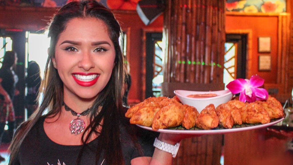 Beautiful Mango's waitress smiling while holding a platter of chicken tenders with dipping sauce